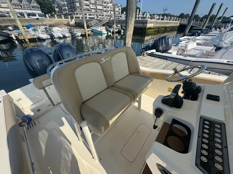 Slide: The Image of 2023 Scout 255 LXF boat interior with dual seats and control panel at marina. - 10