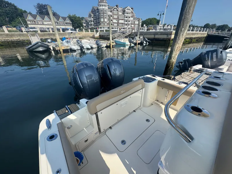 Slide: The Image of 2023 Scout 255 LXF boat docked at marina with twin engines and scenic waterfront view. - 11