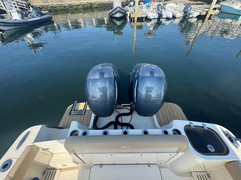 Slide: The Image of 2023 Scout 255 LXF boat with dual outboard engines at a marina dock. - 12