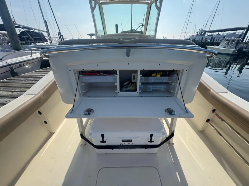 Slide: The Image of 2023 Scout 255 LXF boat with open storage compartments at a marina. - 14