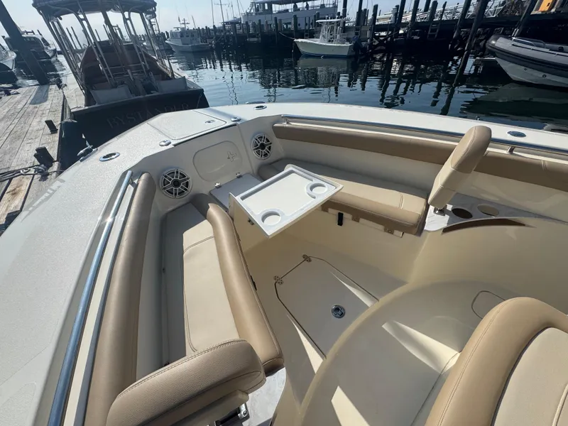 Slide: The Image of 2023 Scout 255 LXF boat interior with beige seating and cup holders at a marina. - 16