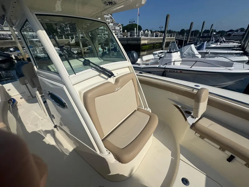 Slide: The Image of 2023 Scout 255 LXF boat interior with beige seating at a marina. - 21
