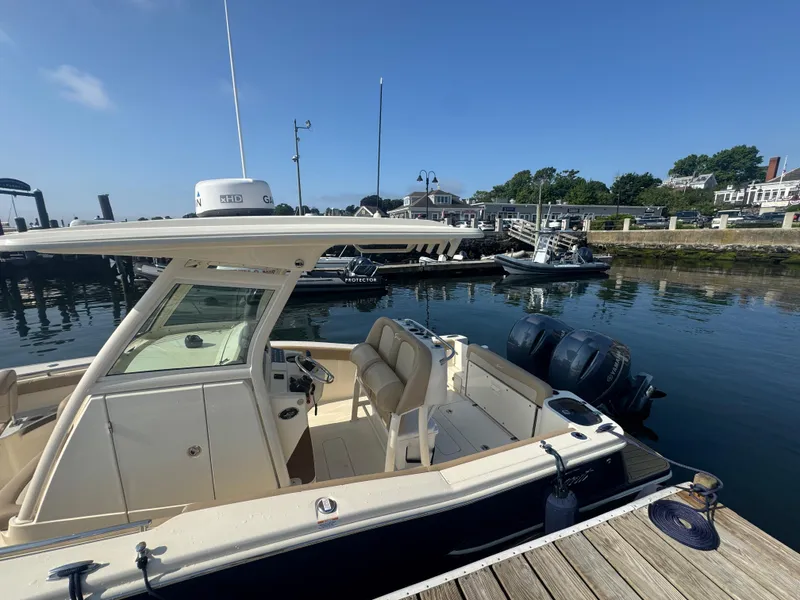 Slide: The Image of 2023 Scout 255 LXF boat docked at a marina under clear blue skies. - 26