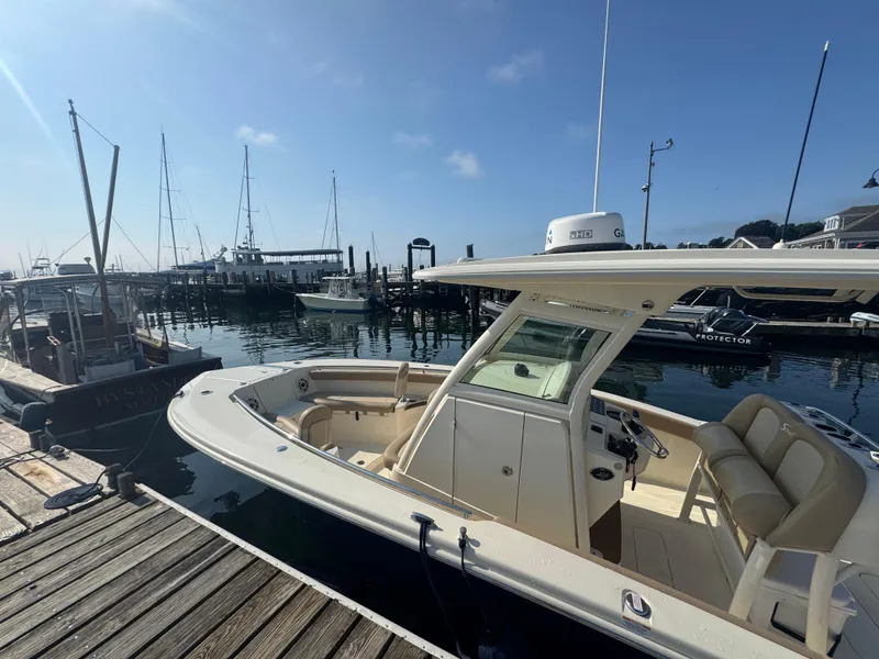 Slide: The Image of 2023 Scout 255 LXF boat docked at marina under clear blue sky. - 27