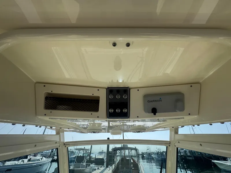 Slide: The Image of 2023 Scout 255 LXF boat dashboard with Garmin equipment, marina view in background. - 30