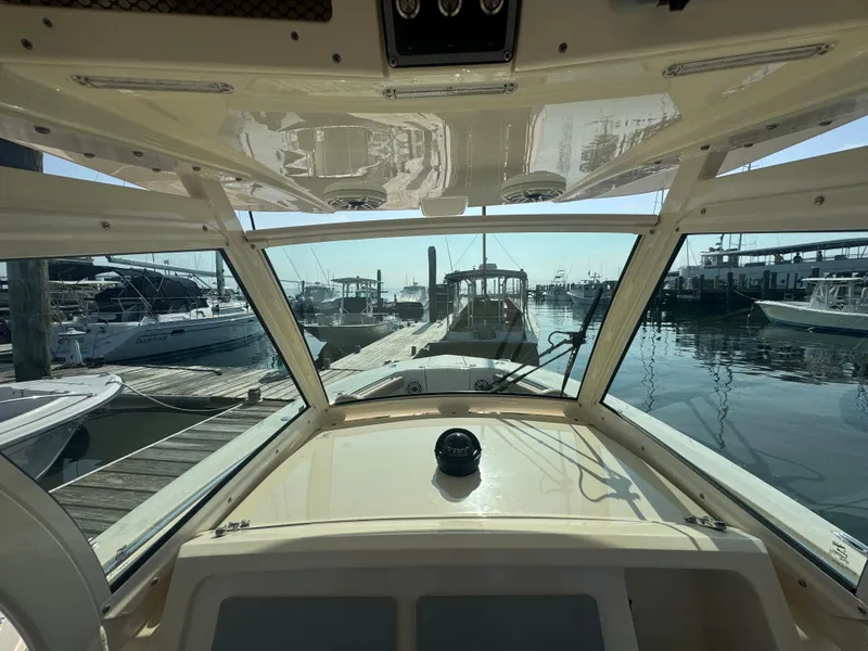 Slide: The Image of 2023 Scout 255 LXF boat interior view at marina, showcasing helm and docked boats. - 32