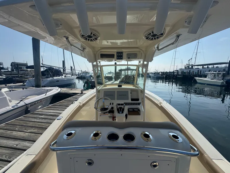 Slide: The Image of 2023 Scout 255 LXF boat docked at marina, featuring helm and controls. - 33
