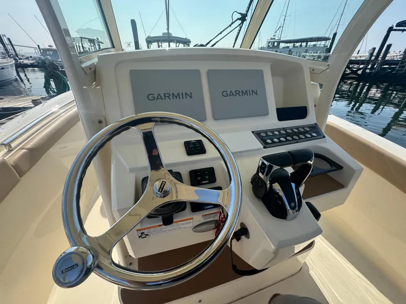 Slide: The Image of 2023 Scout 255 LXF boat helm with Garmin displays and steering wheel. - 40