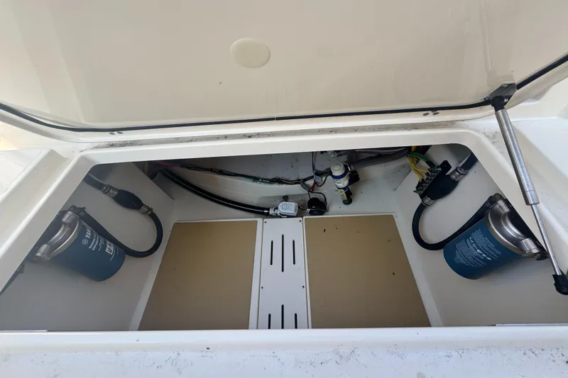 Slide: The Image of 2023 Scout 255 LXF boat storage compartment with visible filters and wiring. - 43