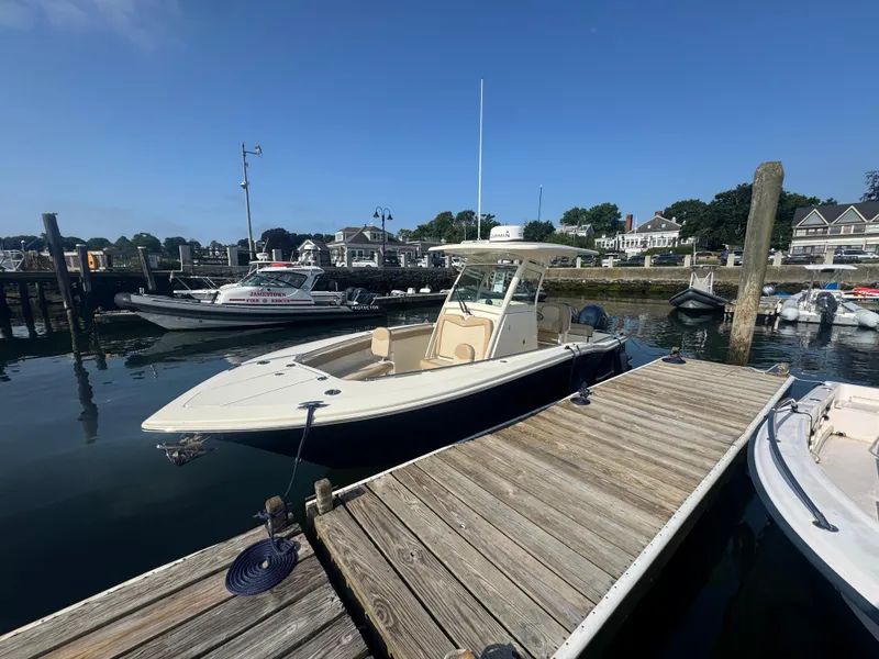 Slide: The Image of 2023 Scout 255 LXF boat docked at a marina under clear blue skies. - 5