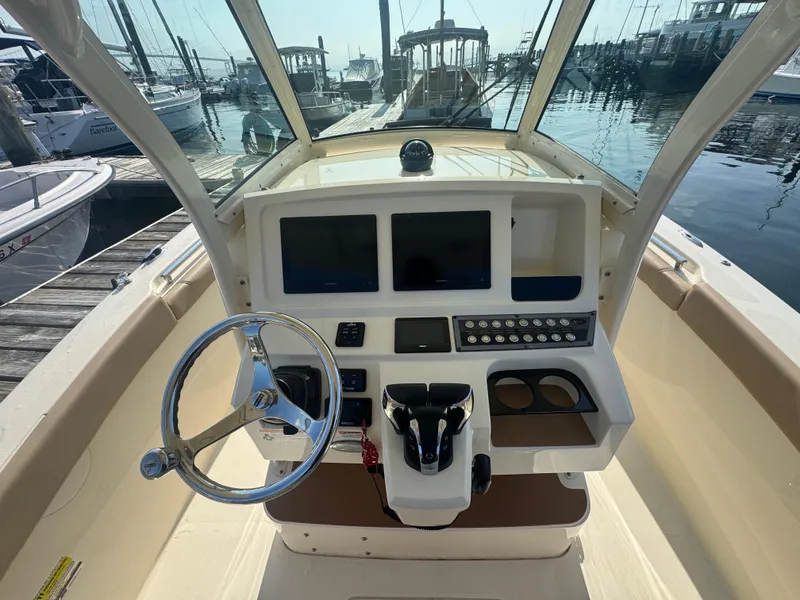 Slide: The Image of 2023 Scout 255 LXF boat dashboard with steering wheel and control panel at marina. - 7