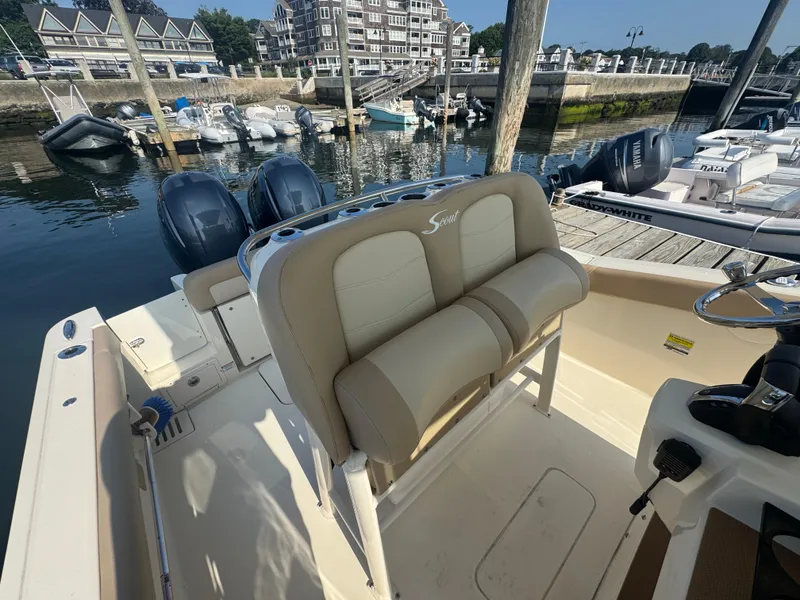 Slide: The Image of 2023 Scout 255 LXF boat interior with dual engines at a marina dock. - 9