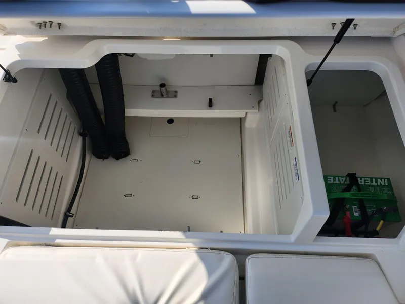 Slide: The Image of 2021 Bayliner DX 2000 boat storage compartment with visible battery and ventilation hoses. - 24