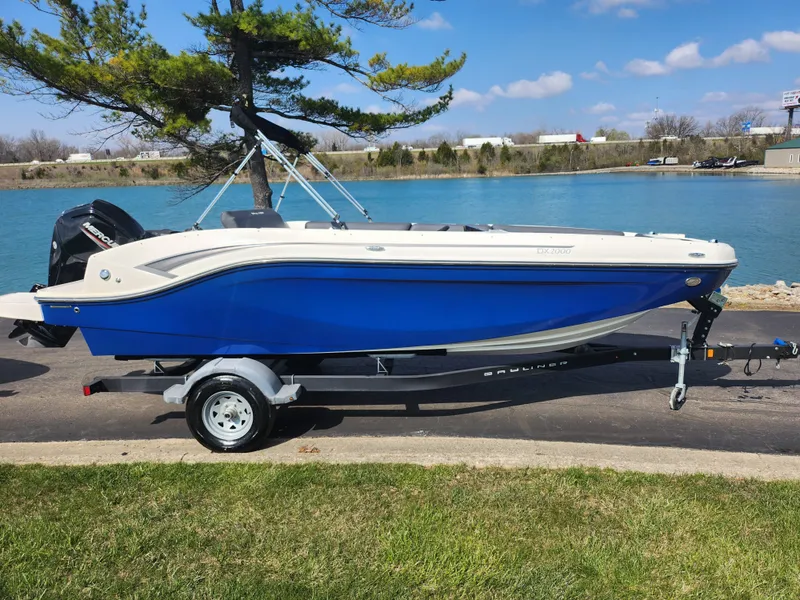 Slide: The Image of 2021 Bayliner DX 2000 boat on trailer by a lake, under a clear blue sky. - 9