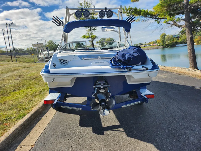 Slide: The Image of 2012 Crownline 195 SS boat parked near a lake, showcasing rear view and propeller. - 2
