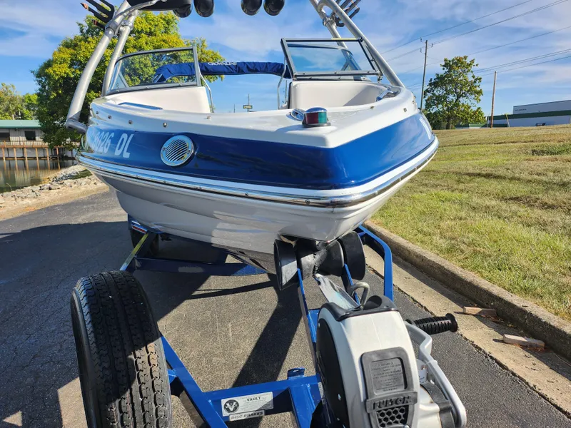 Slide: The Image of 2012 Crownline 195 SS boat on trailer, blue and white, parked outdoors. - 6