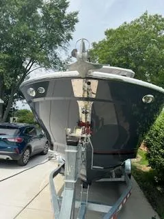 Slide: The Image of 2023 Solara S-250 DC boat on trailer, parked in driveway with trees in background. - 2