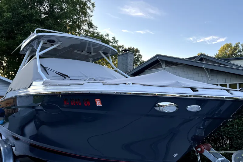Slide: The Image of 2023 Solara S-250 DC boat with cover, parked near a house. - 5