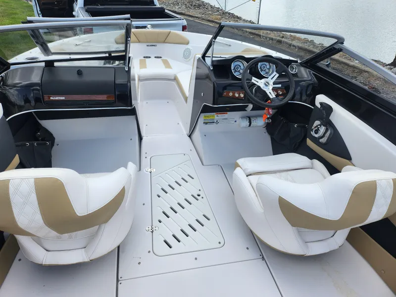 Slide: The Image of 2016 Glastron GT 205 boat interior with white and tan seating, steering wheel, and dashboard. - 12