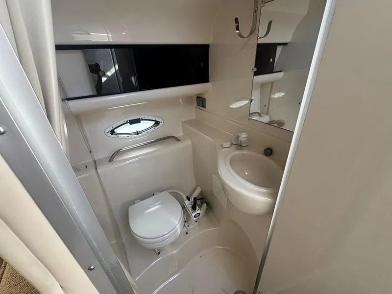 Slide: The Image of Compact bathroom in a 2001 Bayliner 2855 Ciera boat, featuring a toilet, sink, and mirror. - 10