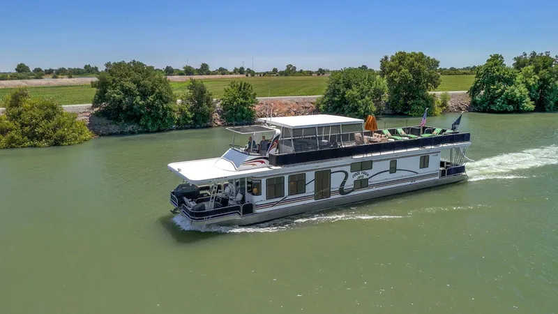 Slide: The Image of 2007 American Waterways Widebody houseboat cruising on a scenic river with lush greenery. - 13
