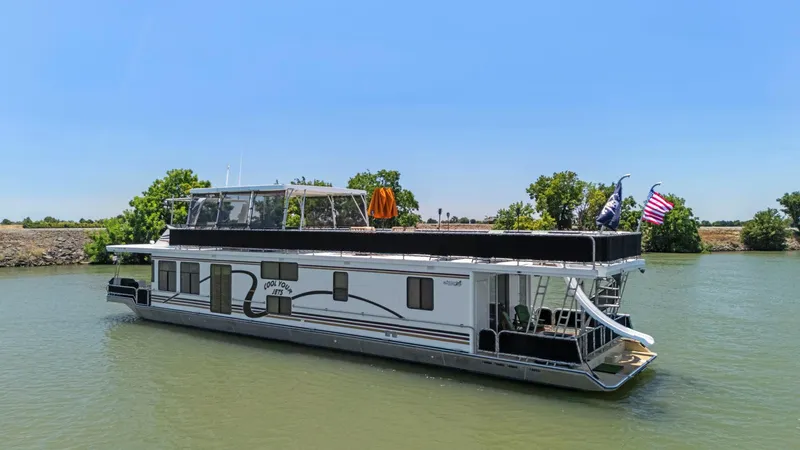 Slide: The Image of 2007 American Waterways Widebody houseboat on a calm river, clear sky background. - 2