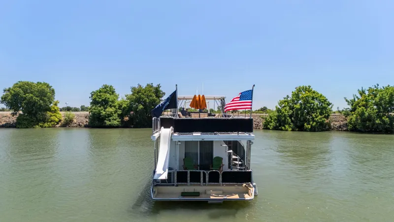 Slide: The Image of Houseboat on a river, American Waterways Widebody 2007, with flags and slide, surrounded by trees. - 3