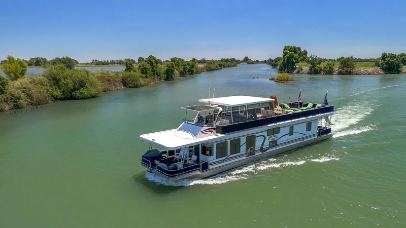 Slide: The Image of 2007 American Waterways Widebody houseboat cruising on a scenic river with lush greenery. - 33