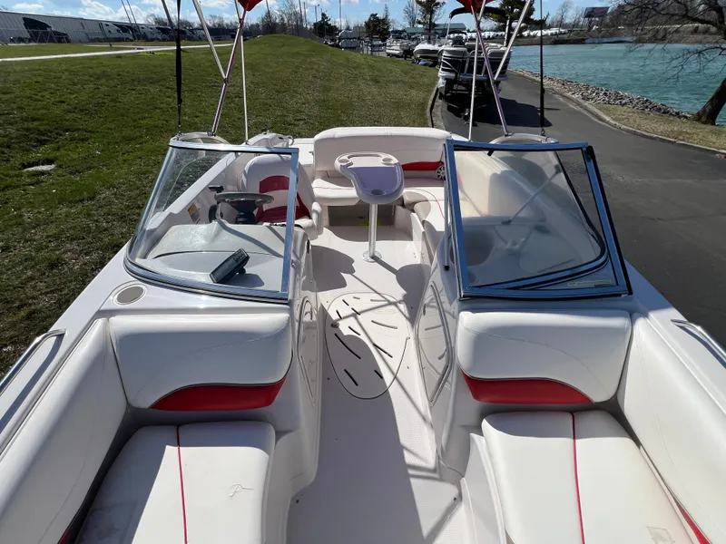 Slide: The Image of 2006 Tahoe 204 WT boat interior with white and red seating, docked by a riverside. - 23
