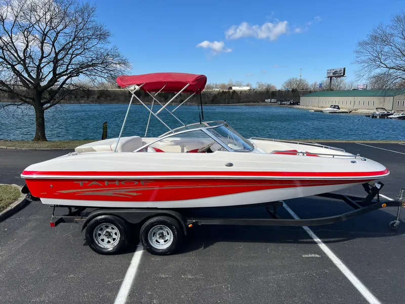 Slide: The Image of 2006 Tahoe 204 WT boat with red accents on a trailer by a lake. - 4
