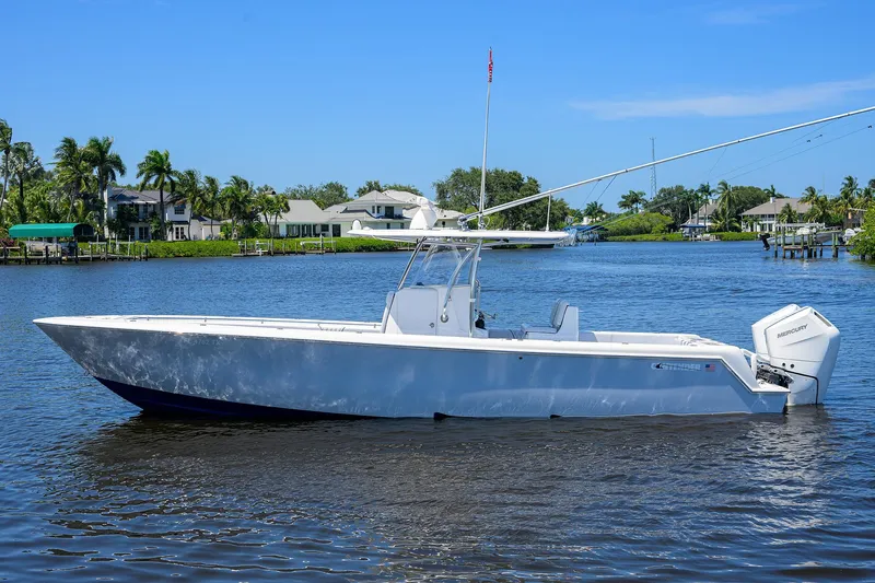 Slide: The Image of 2025 Contender 35 ST boat on a calm river with houses and palm trees. - 0