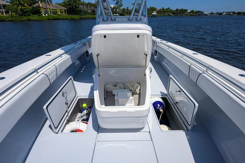 Slide: The Image of 2025 Contender 35 ST boat deck with open storage compartments on a calm waterway. - 27