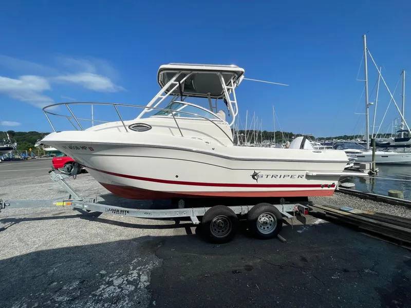 Slide: The Image of 2018 Striper 200 Walkaround boat on trailer at marina, clear blue sky background. - 1