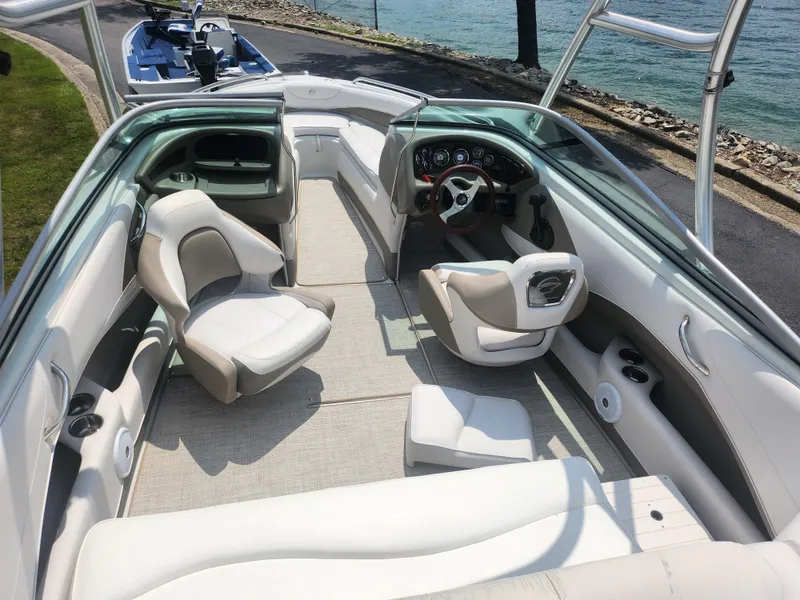 Slide: The Image of 2014 Crownline 21 SS boat interior with seating and steering wheel, docked by the water. - 10