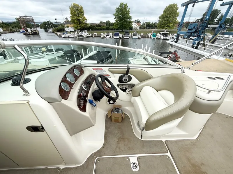 Slide: The Image of 2006 Sea Ray 240 Sundeck helm with steering wheel, gauges, and seating at marina. - 10