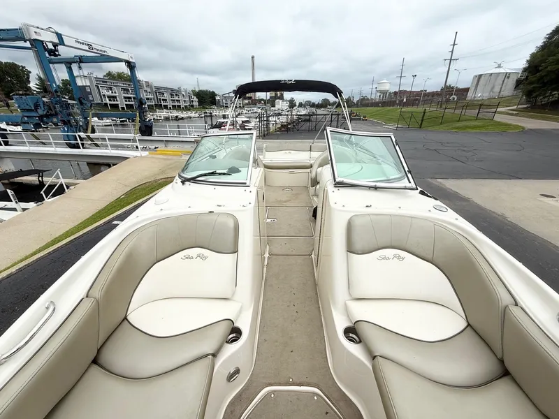 Slide: The Image of 2006 Sea Ray 240 Sundeck boat with spacious seating, docked near a marina. - 11