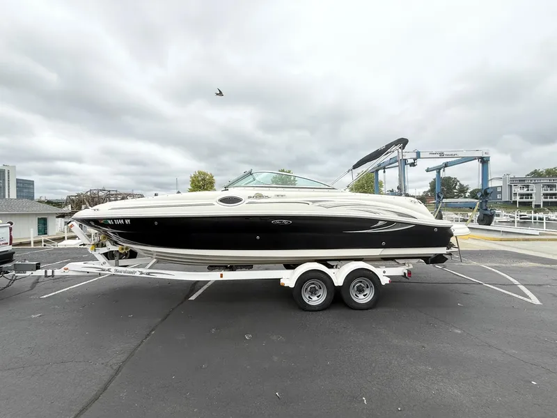 Slide: The Image of 2006 Sea Ray 240 Sundeck boat on trailer, parked in marina lot under cloudy sky. - 4