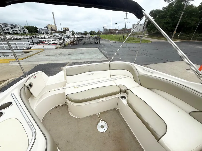 Slide: The Image of 2006 Sea Ray 240 Sundeck boat interior with beige seating, docked at marina. - 7