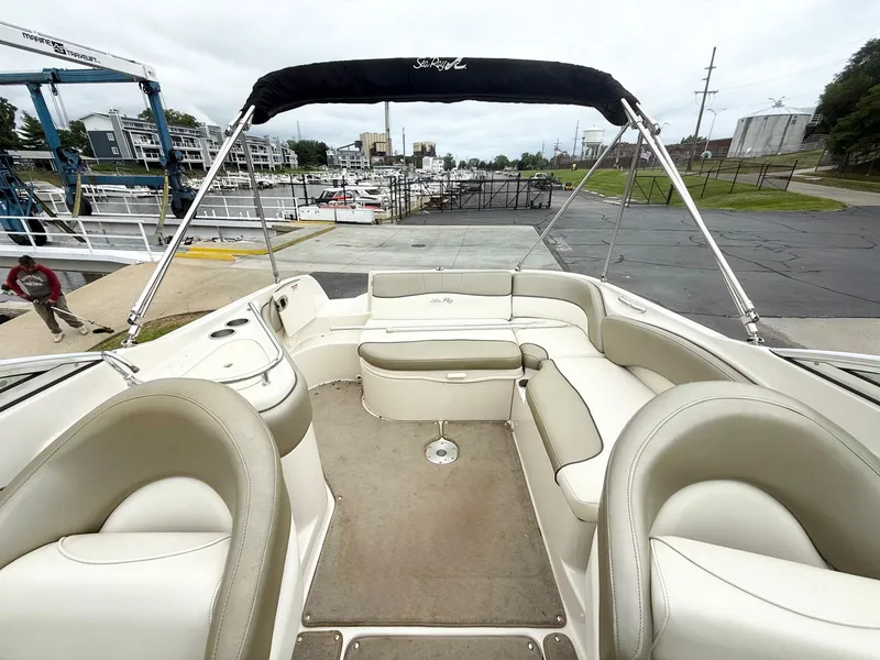 Slide: The Image of 2006 Sea Ray 240 Sundeck boat interior with beige seating and canopy at marina. - 8
