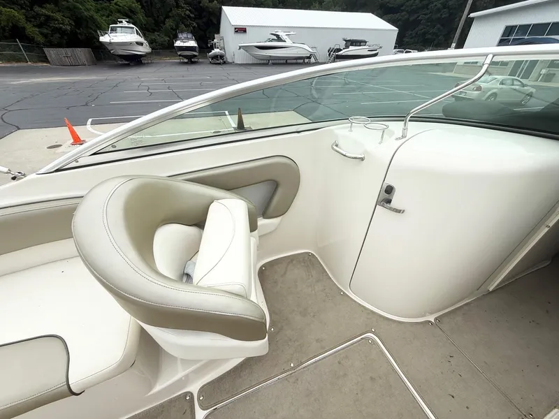 Slide: The Image of 2006 Sea Ray 240 Sundeck interior with seating and storage, parked near other boats. - 9