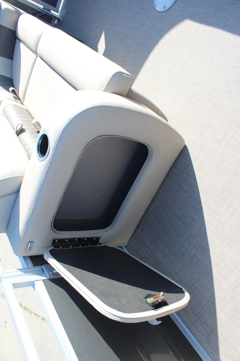 Slide: The Image of 2025 Sun Tracker Party Barge 22 RF DLX interior storage compartment with open seat and cup holder. - 18
