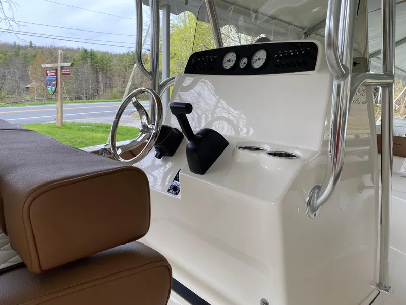 Slide: The Image of 2026 Pioneer 202 Islander boat interior with steering wheel, gauges, and brown seating. - 11