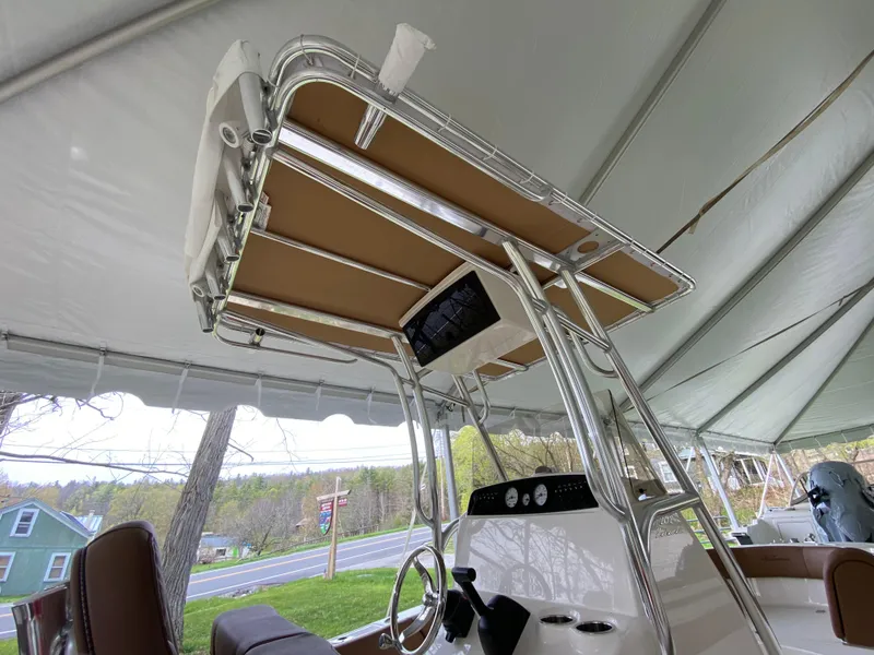 Slide: The Image of 2026 Pioneer 202 Islander boat with T-top and console under a canopy. - 14