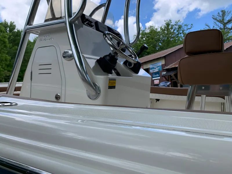 Slide: The Image of 2026 Pioneer 202 Islander boat interior with steering wheel and seating, under a clear blue sky. - 15
