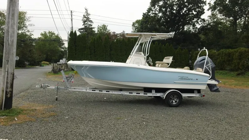 Slide: The Image of 2026 Pioneer 202 Islander boat on trailer, parked on gravel road. - 2