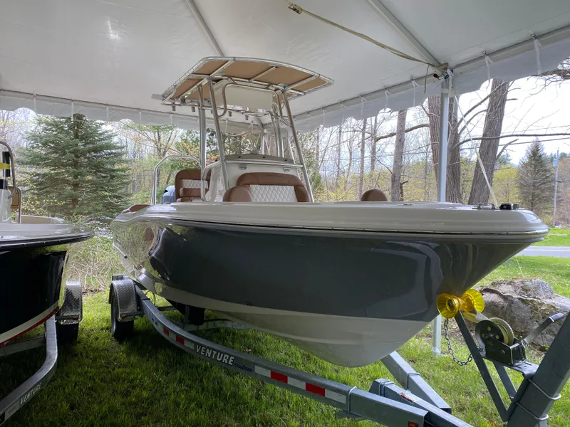 Slide: The Image of 2026 Pioneer 202 Islander boat on trailer under tent, surrounded by trees. - 25