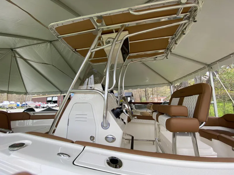 Slide: The Image of 2026 Pioneer 202 Islander boat interior with brown seating and steering console under a canopy. - 5