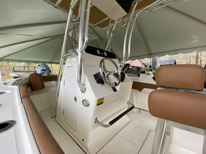 Slide: The Image of 2026 Pioneer 202 Islander boat interior with steering console and brown seating under canopy. - 7