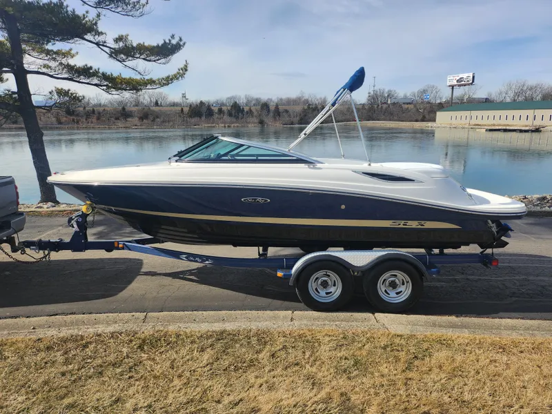Slide: The Image of 2014 Sea Ray 210 SLX boat on trailer by a lake. - 9
