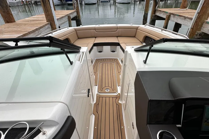 Slide: The Image of 2021 Sea Ray SDX 290 Outboard boat interior with tan seating and wooden deck. - 10